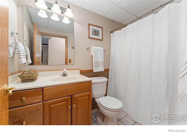 full bath with tile patterned floors, toilet, a drop ceiling, and vanity