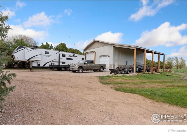 exterior space with a detached garage, an outdoor structure, and dirt driveway