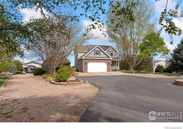 traditional-style house with aphalt driveway, an attached garage, and brick siding