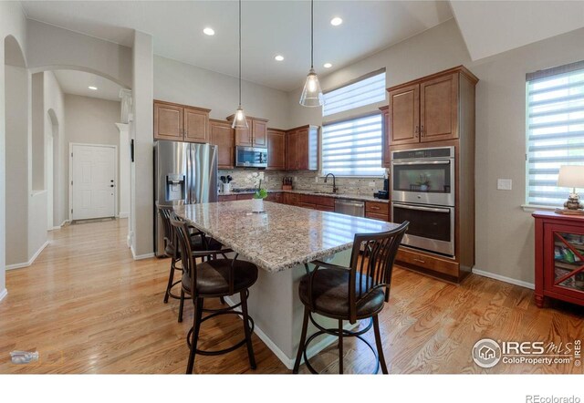kitchen featuring a kitchen island, a kitchen breakfast bar, a sink, backsplash, and stainless steel appliances