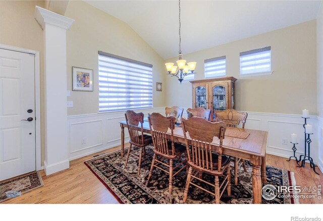 dining room featuring a healthy amount of sunlight, wainscoting, light wood finished floors, and a notable chandelier