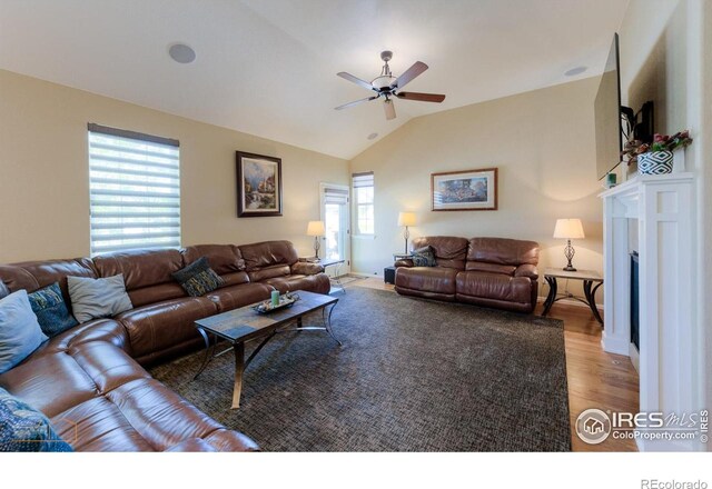 living room with light wood-style floors, ceiling fan, a fireplace, and lofted ceiling