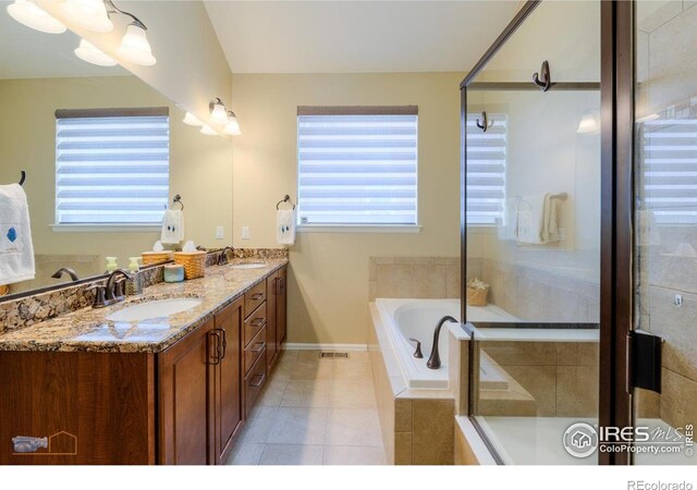bathroom featuring double vanity, a bath, a stall shower, a sink, and tile patterned floors