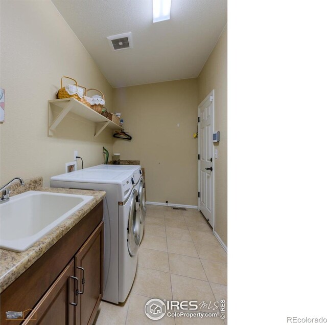 laundry area with independent washer and dryer, cabinet space, a sink, light tile patterned floors, and baseboards