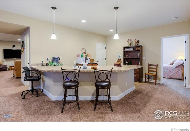 kitchen featuring light carpet, a kitchen breakfast bar, a peninsula, decorative light fixtures, and baseboards