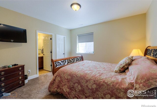 carpeted bedroom featuring baseboards and connected bathroom
