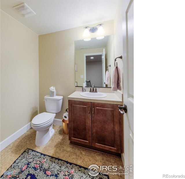 half bath featuring toilet, baseboards, visible vents, and vanity