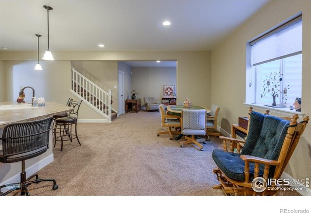 carpeted dining area with recessed lighting, baseboards, a sink, and stairway