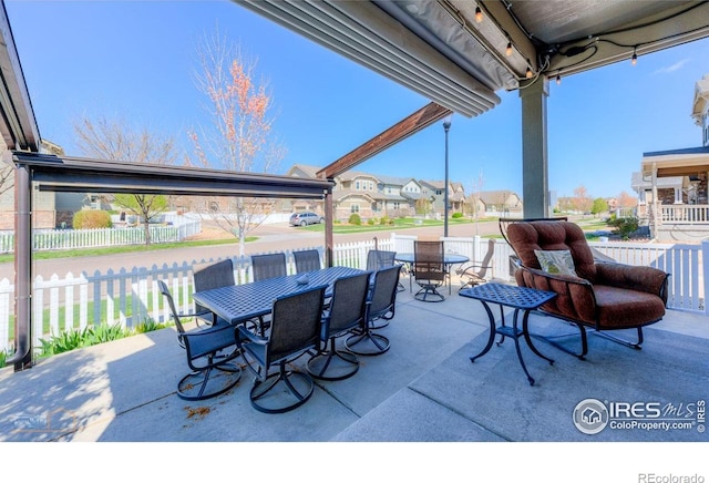 view of patio / terrace featuring fence, outdoor dining space, and a residential view