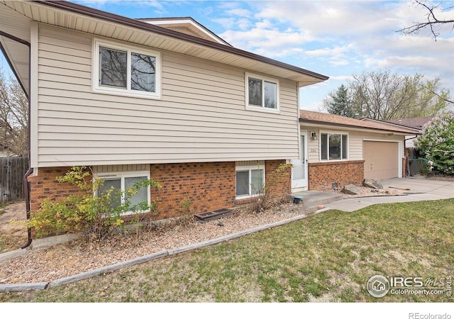 split level home with brick siding, fence, a front lawn, concrete driveway, and an attached garage