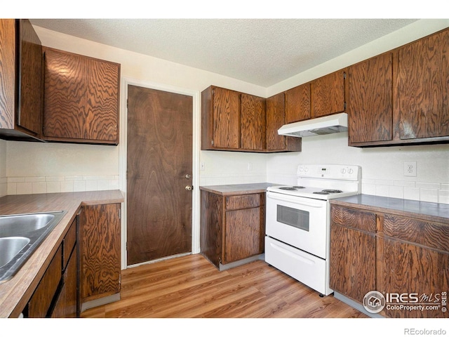 kitchen featuring a textured ceiling, white range with electric cooktop, a sink, under cabinet range hood, and light wood-style flooring