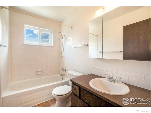 full bathroom with decorative backsplash, wood finished floors, vanity, toilet, and tub / shower combination