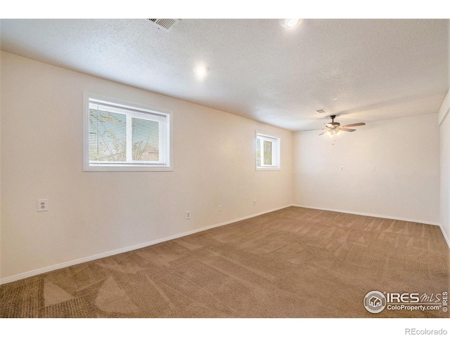 spare room featuring baseboards, a ceiling fan, carpet, and a textured ceiling