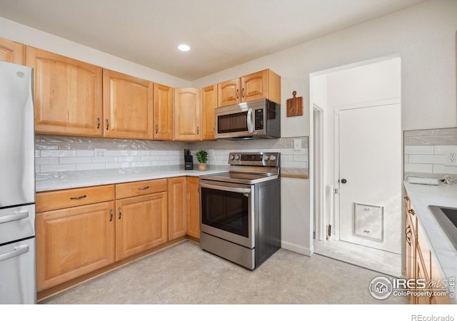 113 Balsam St, Fort Morgan, CO 80701 - kitchen with decorative backsplash, appliances with stainless steel finishes, light brown cabinetry, light countertops, and a sink