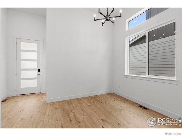 spare room with baseboards, wood finished floors, and a chandelier