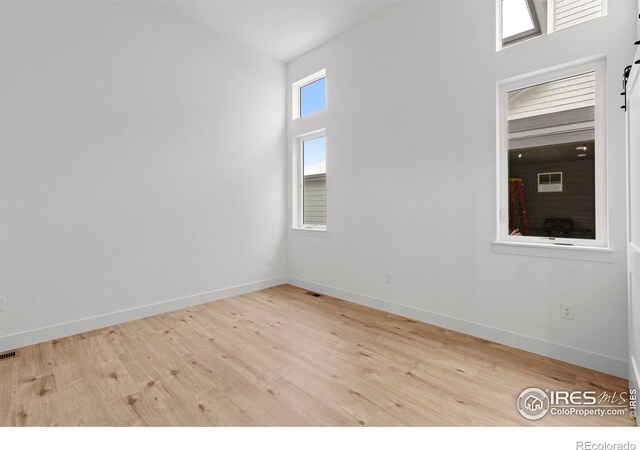 empty room with baseboards, visible vents, and wood finished floors