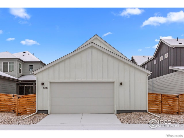 view of front of house with board and batten siding, an attached garage, fence, and driveway