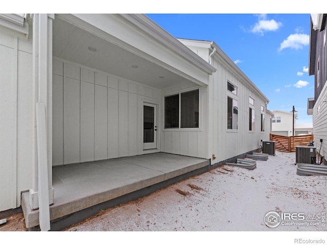 exterior space featuring central AC unit, board and batten siding, a patio area, and fence
