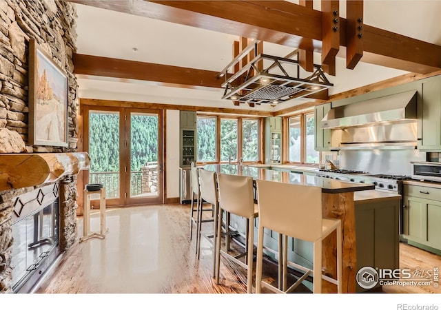 2307 Magnolia Dr, Nederland, CO 80466 - kitchen with wall chimney range hood, a center island, beam ceiling, green cabinetry, and a breakfast bar