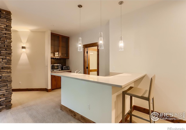2307 Magnolia Dr, Nederland, CO 80466 - kitchen featuring a peninsula, a kitchen bar, light countertops, stainless steel microwave, and brown cabinets