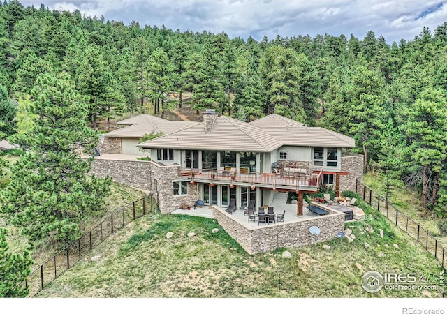 2307 Magnolia Dr, Nederland, CO 80466 - back of property featuring a wooden deck, stone siding, a fenced backyard, a patio area, and a lawn