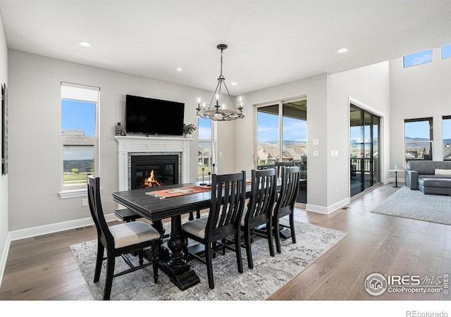 3295 Heron Lakes Pkwy, Berthoud, CO 80513 - dining space with a glass covered fireplace, wood finished floors, baseboards, recessed lighting, and a chandelier