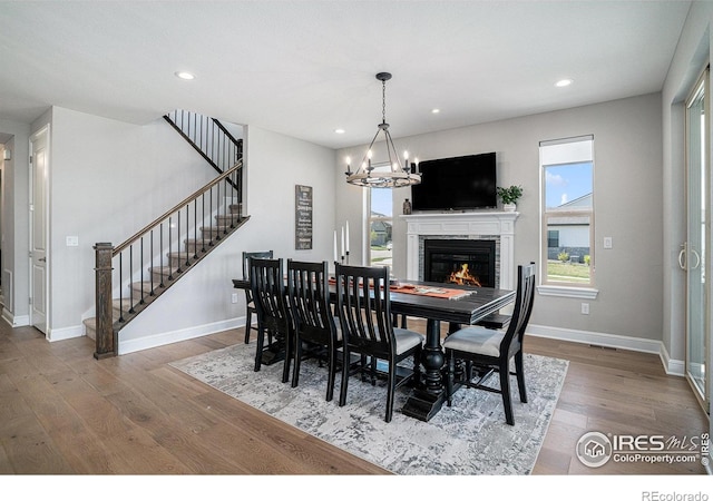 3295 Heron Lakes Pkwy, Berthoud, CO 80513 - dining area featuring an inviting chandelier, wood finished floors, a healthy amount of sunlight, and stairway