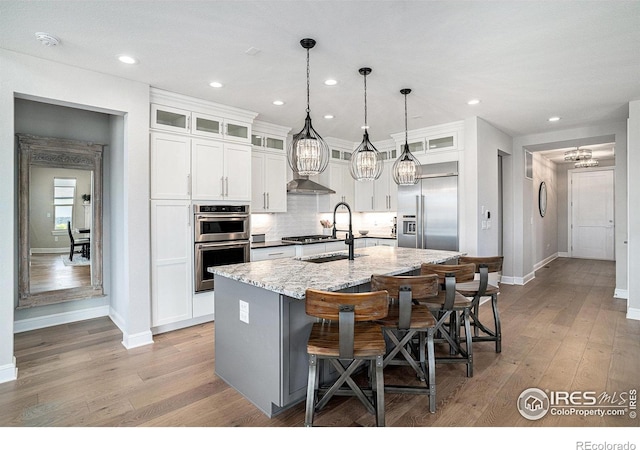 3295 Heron Lakes Pkwy, Berthoud, CO 80513 - kitchen featuring baseboards, a chandelier, a center island with sink, and stainless steel appliances