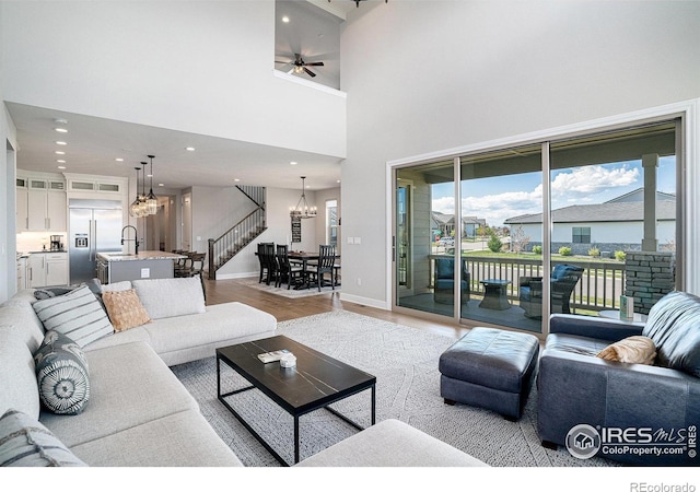 3295 Heron Lakes Pkwy, Berthoud, CO 80513 - living area featuring a high ceiling, ceiling fan with notable chandelier, recessed lighting, baseboards, and light wood-type flooring