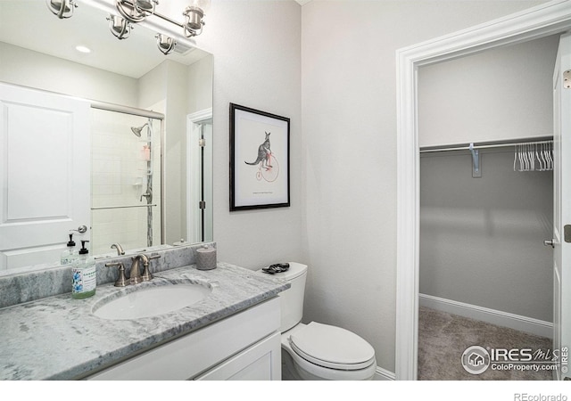 3295 Heron Lakes Pkwy, Berthoud, CO 80513 - bathroom with vanity, toilet, baseboards, a walk in closet, and a tile shower