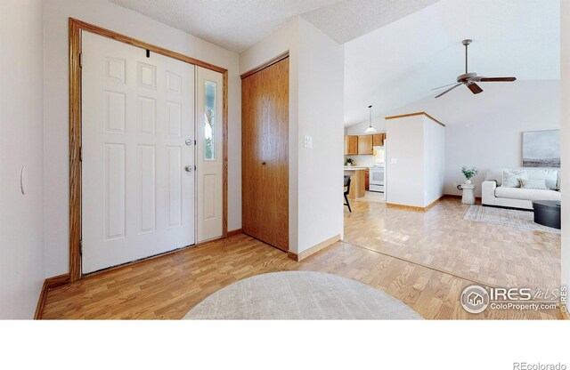 foyer entrance featuring baseboards, ceiling fan, light wood-style flooring, and lofted ceiling