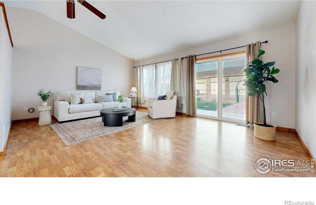 living area with wood finished floors, a ceiling fan, baseboards, and lofted ceiling