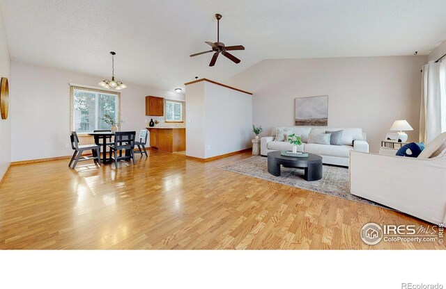 living area featuring baseboards, light wood-style flooring, ceiling fan with notable chandelier, and vaulted ceiling