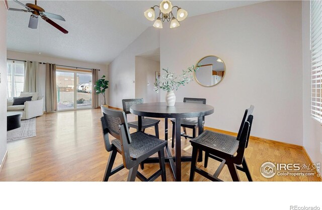 dining room with baseboards, light wood finished floors, ceiling fan with notable chandelier, and vaulted ceiling
