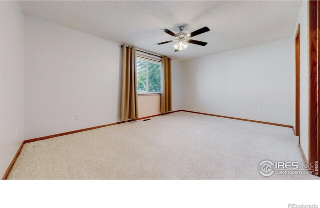 spare room featuring a ceiling fan, baseboards, light carpet, and a textured ceiling
