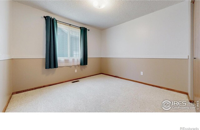 unfurnished room featuring baseboards, carpet flooring, a textured ceiling, and visible vents