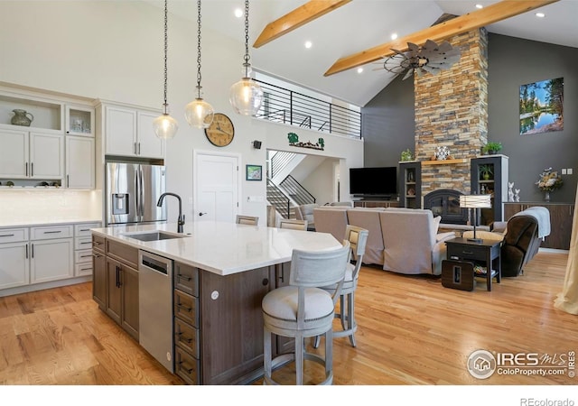 kitchen with a kitchen breakfast bar, high vaulted ceiling, a sink, light wood finished floors, and appliances with stainless steel finishes