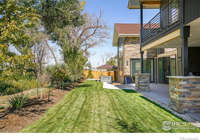 view of yard featuring fence, a patio area, and a balcony