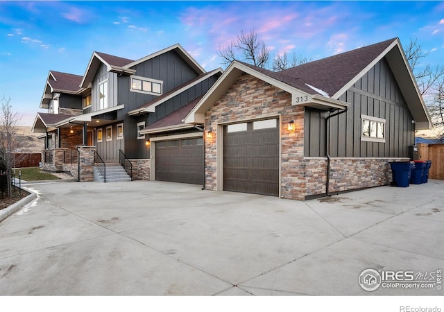 view of front of home featuring board and batten siding, concrete driveway, an attached garage, a shingled roof, and stone siding