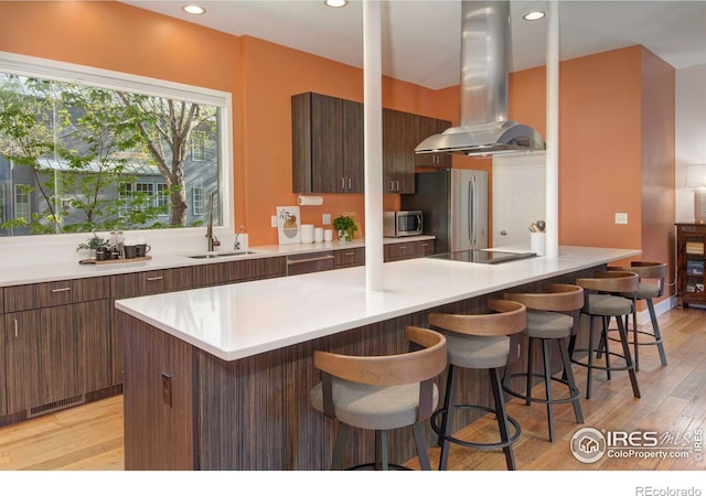 1025 Neon Forest Cir, Longmont, CO 80504 - kitchen featuring island range hood, modern cabinets, a kitchen breakfast bar, light wood finished floors, and recessed lighting