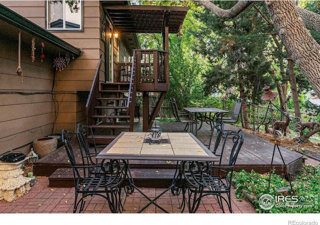 view of patio with a wooden deck, outdoor dining area, and stairway