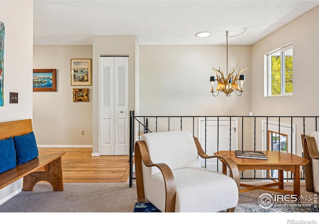sitting room featuring baseboards, carpet, a textured ceiling, and a chandelier
