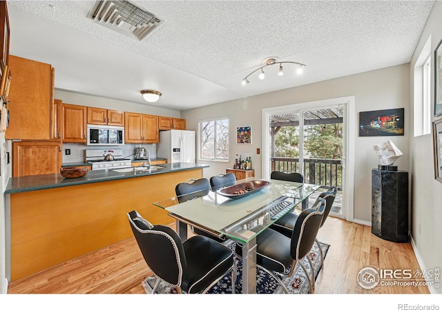 dining room with visible vents, a textured ceiling, and light wood finished floors