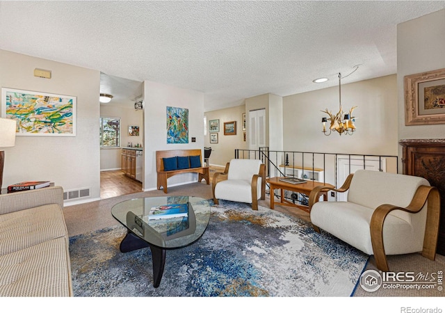 living room with an inviting chandelier, visible vents, baseboards, a textured ceiling, and carpet