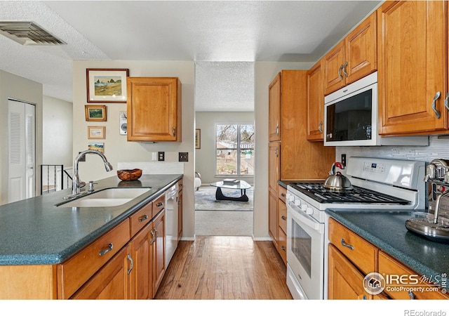 kitchen featuring white gas stove, visible vents, a sink, light wood finished floors, and dishwashing machine