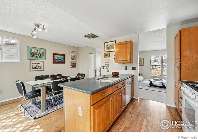 kitchen with a sink, white appliances, light wood-style flooring, and visible vents