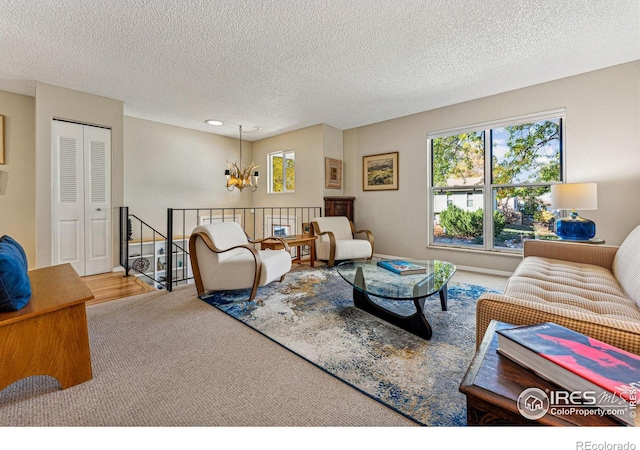 living room featuring carpet floors, a textured ceiling, and a notable chandelier