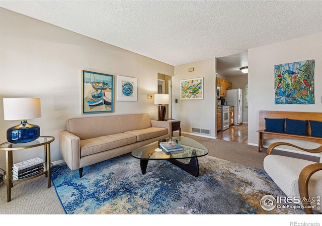 carpeted living room featuring a textured ceiling, baseboards, and visible vents