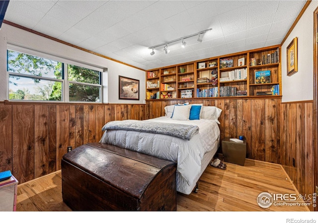 bedroom with wooden walls, wainscoting, and wood-type flooring