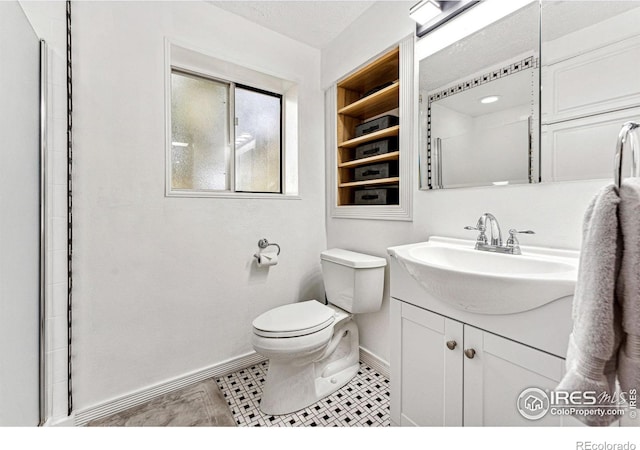 bathroom featuring toilet, baseboards, and vanity